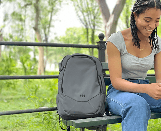 Woman sitting on a bench with a Series 2 Small Alloy Gray Knack Pack next to her