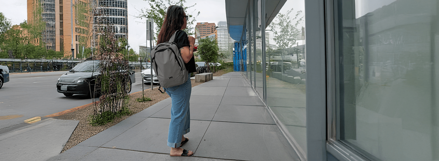 Woman with a small Knack Pack standing on a sidewalk in a city next to a building entrance.